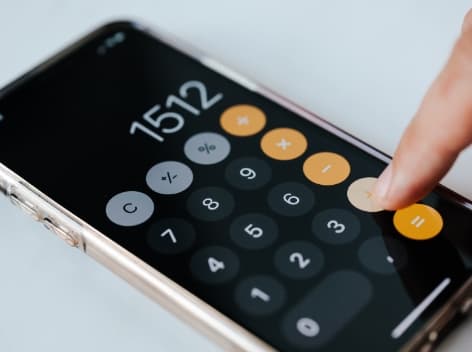 Taxo calculator interface for VAA/ATN benefit in kind calculation. Close-up of finger pressing buttons on smartphone calculator.