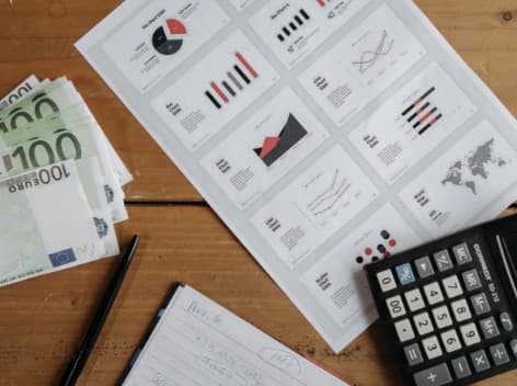 Financial documents and charts with a Euro banknote, illustrating the employer CO2 solidarity contribution calculation.
