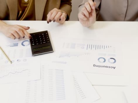 Accounting professional using desk calculator and analyzing paperwork for yearly circulation road tax.