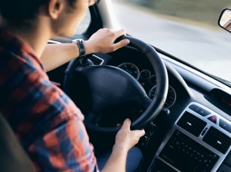 Driver's hands on a steering wheel (over the shoulder view) for BIV/TMC registration tax simulation.